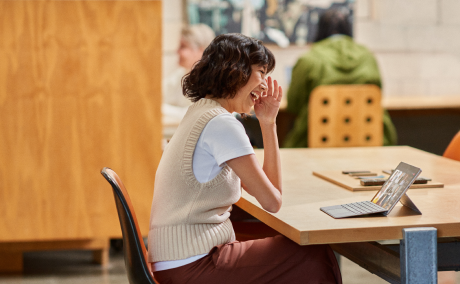 Person sitting at a table talking on a tablet.