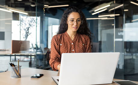 A person looks at their laptop in an office setting.