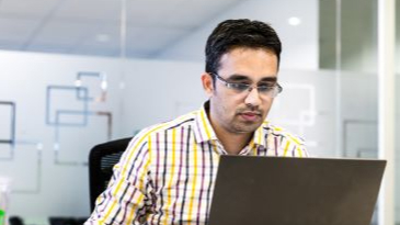 A man with glasses working on laptop