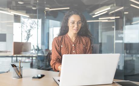 A person looks at their laptop in an office setting.