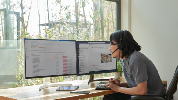 A person reviewing two computer monitors 