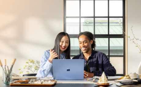 Image of two people at a desk in front of their computer