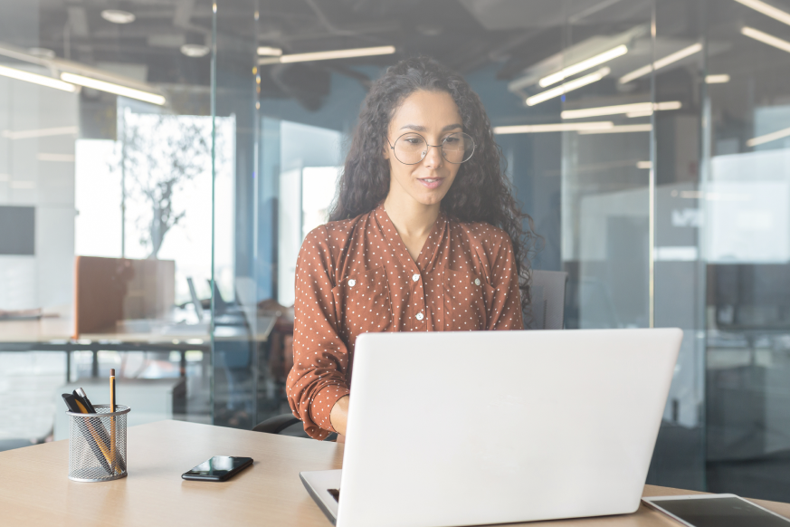 A person looks at their laptop in an office setting.