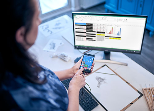 Mulher aponta para o telefone com os dados no monitor