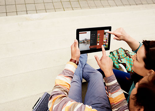 Mulher aponta para o telefone com os dados no monitor.