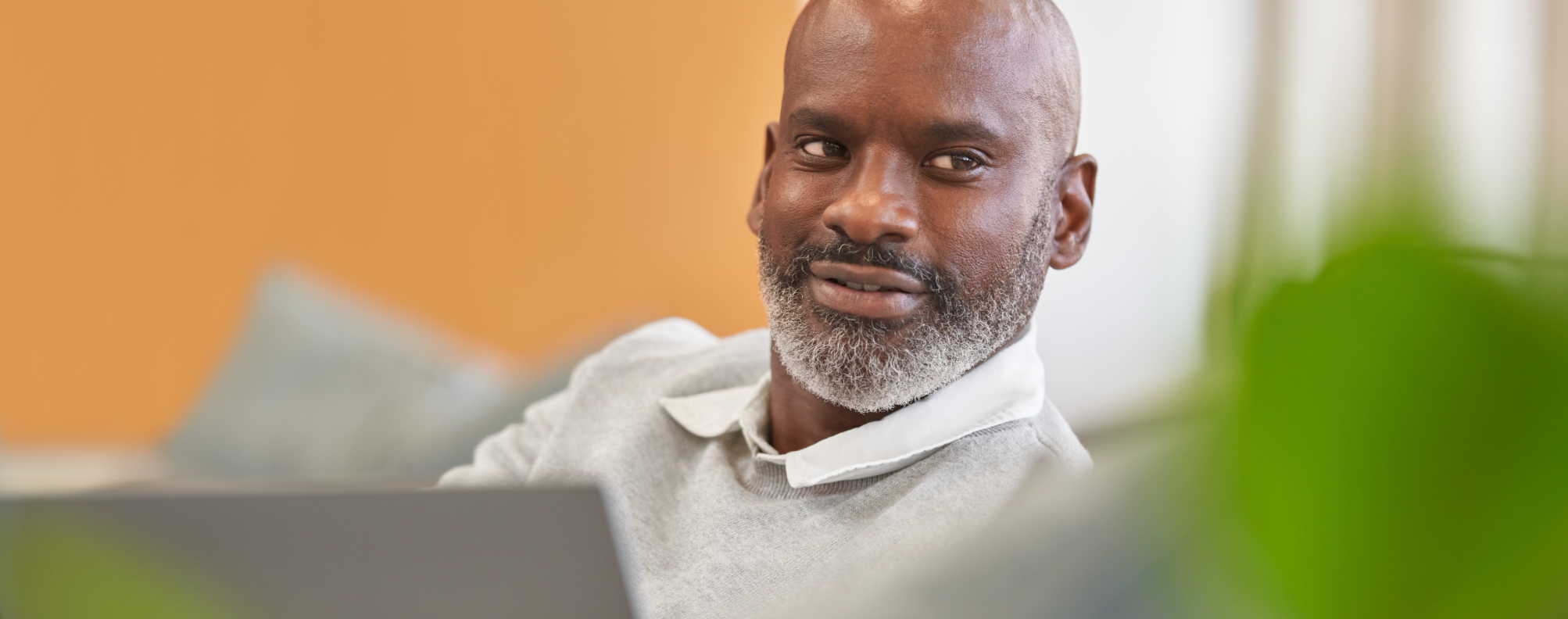 Person using a laptop while seated indoors on a couch.