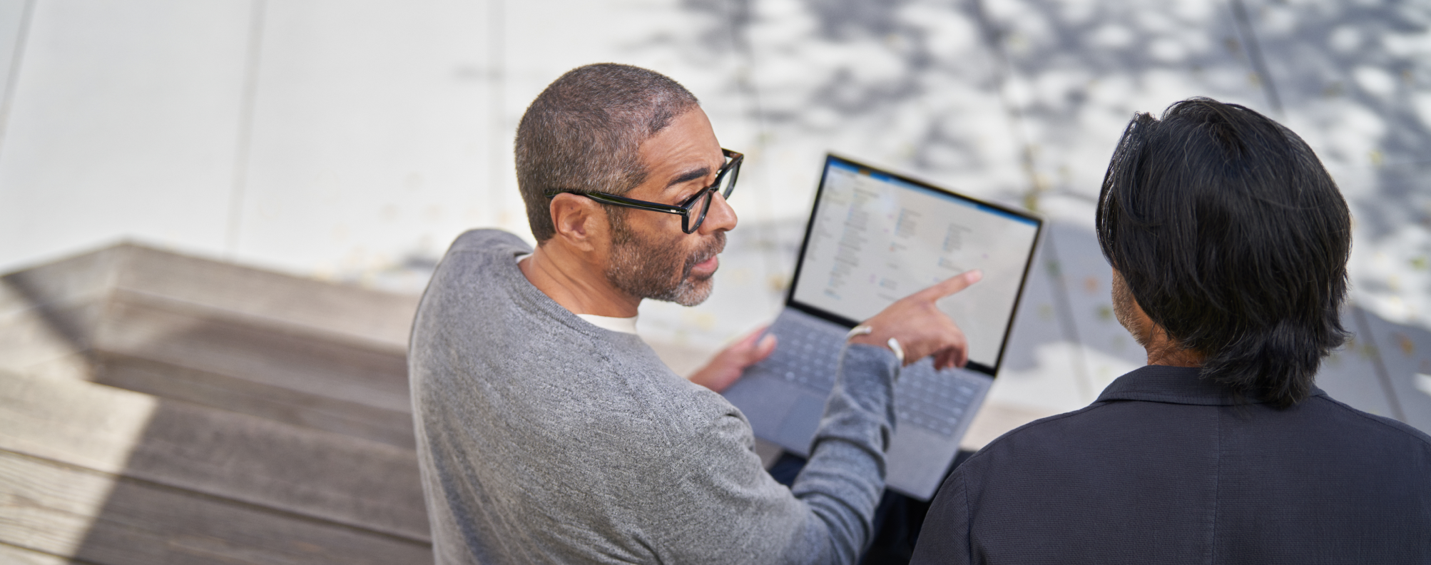 Two people discussing what's displayed on a laptop screen.