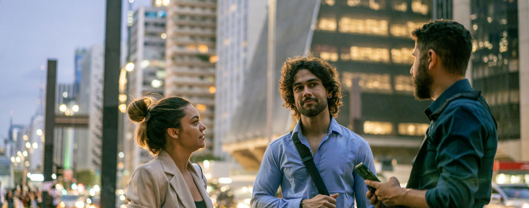 Three people having a conversation on a city street.