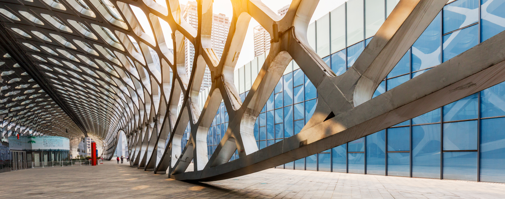 A modern architectural structure with a geometric metal lattice and glass facade illuminated by sunlight, symbolizing innovation and technology.