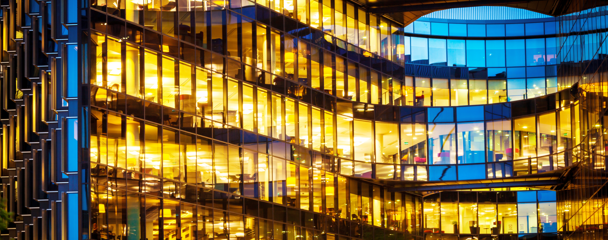 A modern business hub is brightly illuminated at night, showcasing multiple floors and interior space