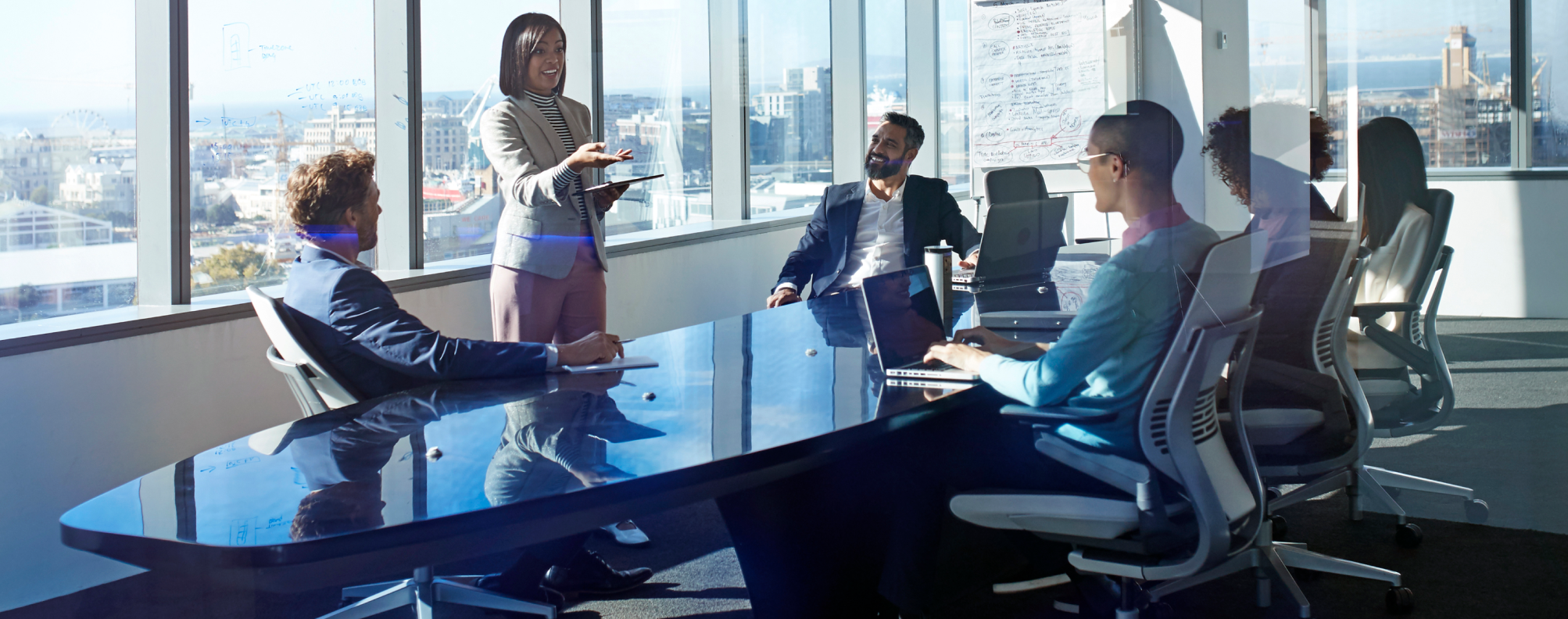 A group of professionals collaborates in a modern conference room with large windows and city views.