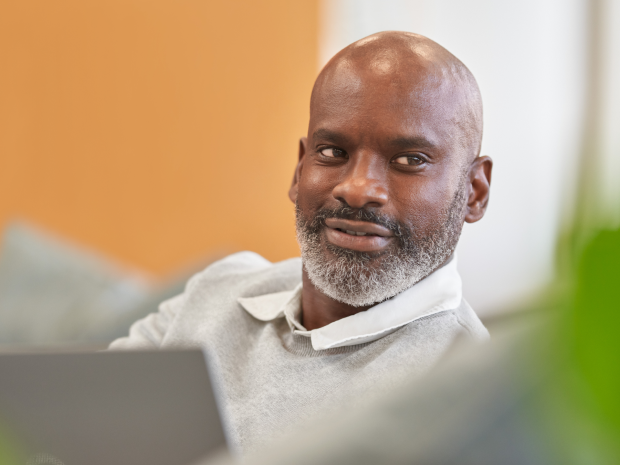 Person using a laptop while seated indoors on a couch.
