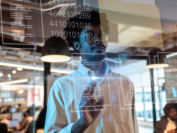 A person interacts with virtual data and file icons on a transparent screen in a modern office setting.