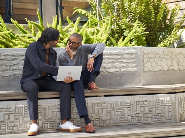 Colleagues collaborating on a laptop in an outdoor courtyard.