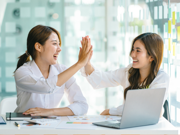 Two colleagues in a conference room giving each other a high five.