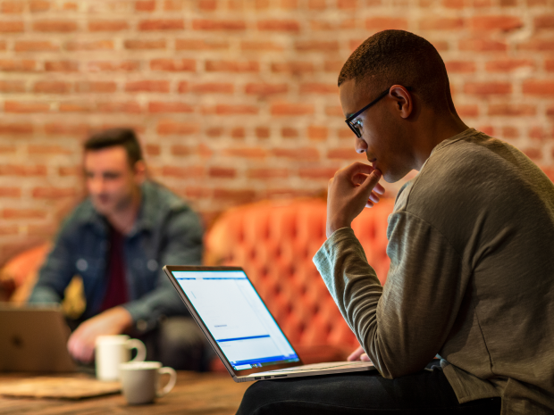 A person looks at their laptop in an office setting.