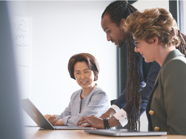 Three attorneys collaborating around a laptop in a conference room