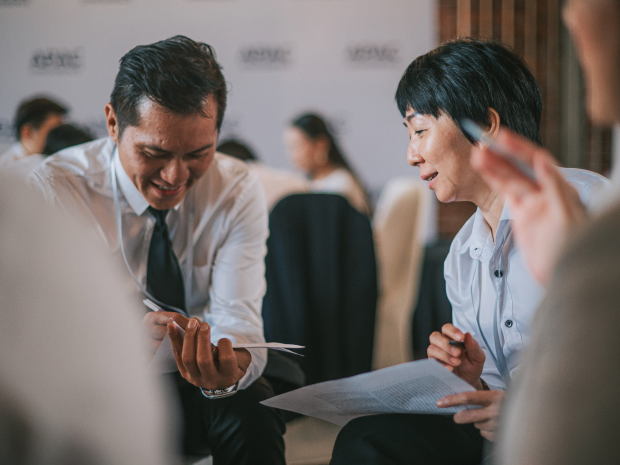 Two professionals seated in discussion, reviewing documents during a business meeting in a conference setting.