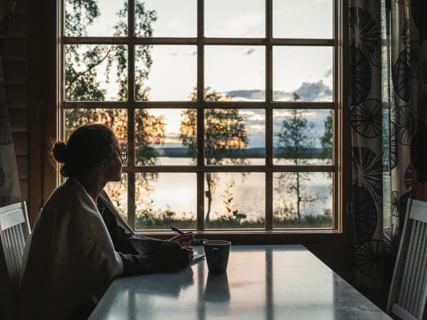 Woman gazing out window at a lake scene