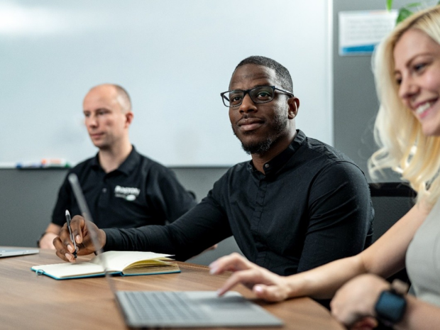 Three people sitting at a table in a conference room.