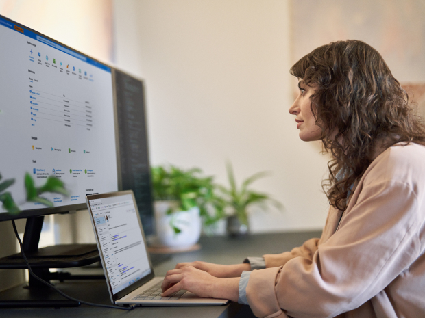 A knowledge worker sitting at a desk using a laptop and an external monitor.