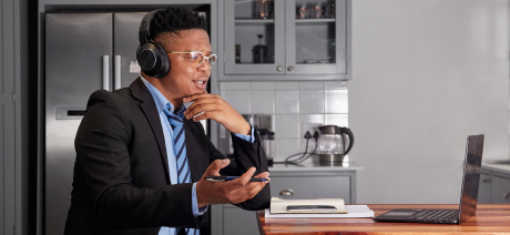 A businessman with headphones having a call in his laptop
