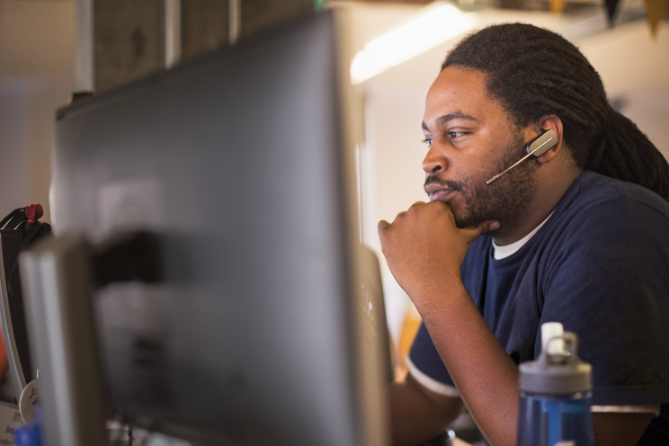 A person with a headset in front of a computer screen.