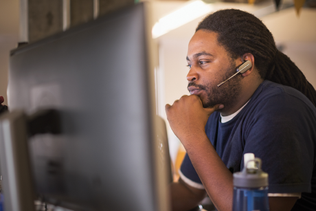 A person with a headset in front of a computer screen.