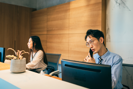 Two people working at a front desk one on the phone.