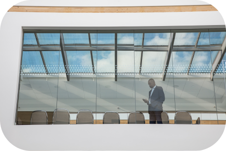 Business professional standing in glass conference room.