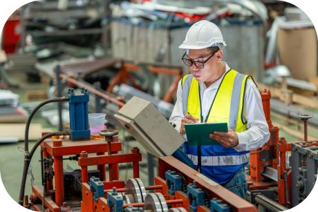 Person with a clipboard observing factory machinery