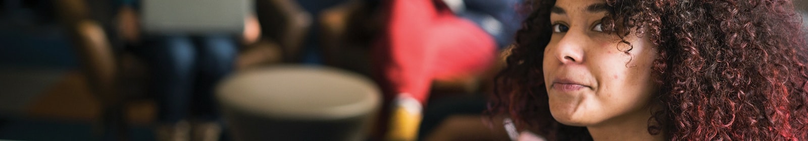 Woman listens in meeting with colleagues.