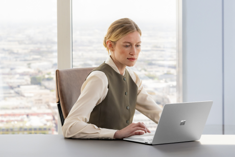 A person working on a laptop in a boardroom.