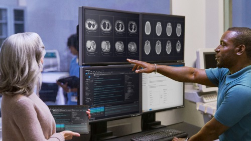 Two people review medical imaging on multiple screens