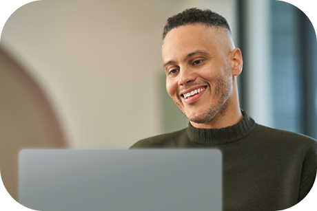 A person looking at a laptop and smiling