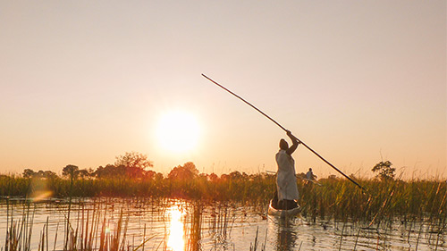 Woman standing in and paddling a canoe