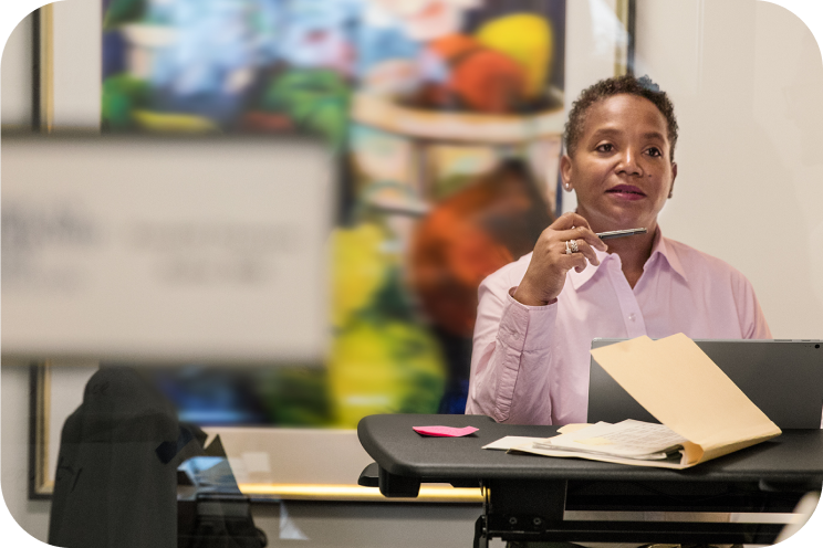 A person is working with a laptop and files at a standing desk