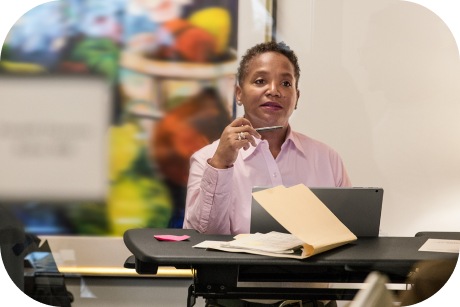 A person is working with a laptop and files at a standing desk