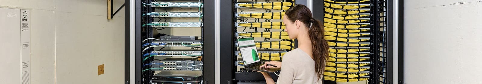 A female IT employee analyzes data in front of a server