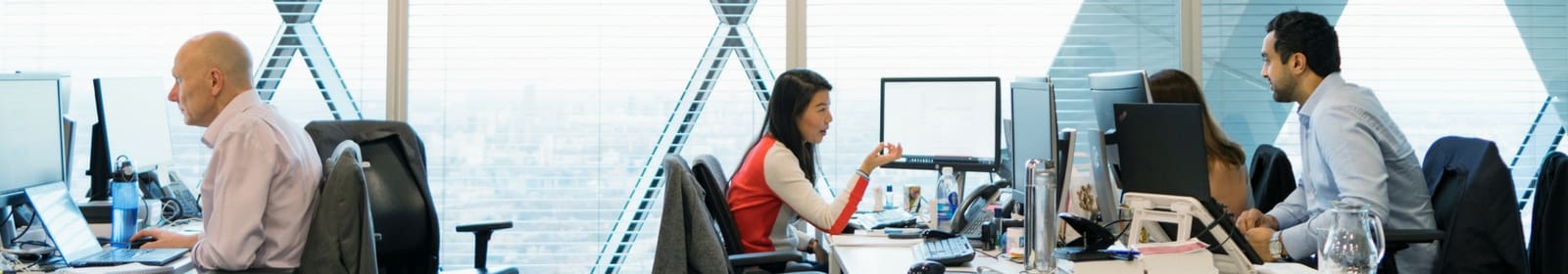 Four colleagues sit and work at their desks in an office