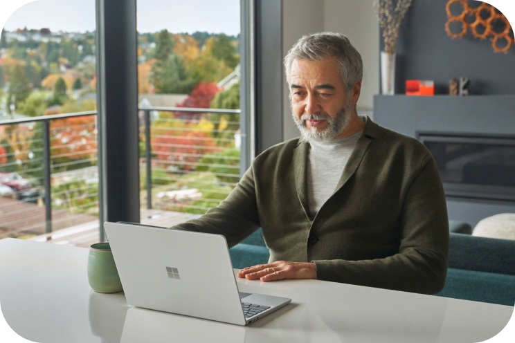 A person sitting at a table looking at a laptop