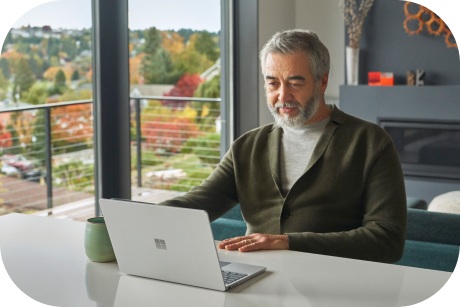 A person sitting at a table looking at a laptop