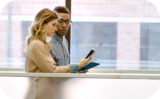 Two people walking and looking at a cell phone