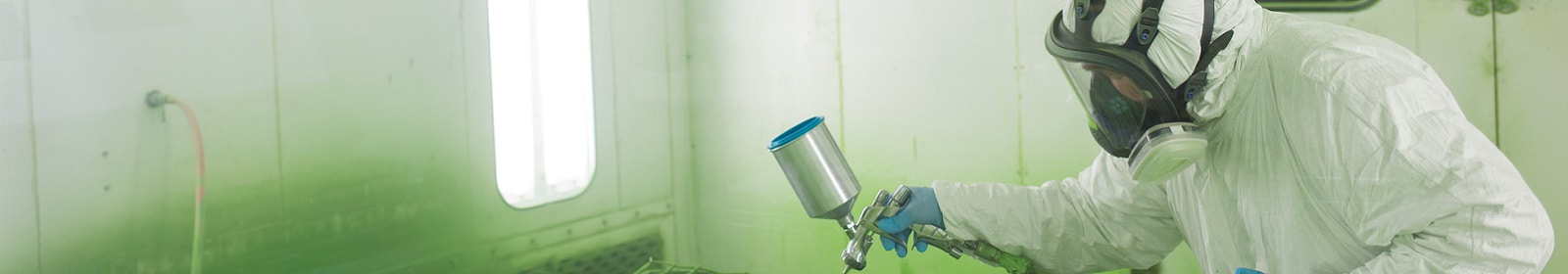 A worker wearing a respirator applies a coating