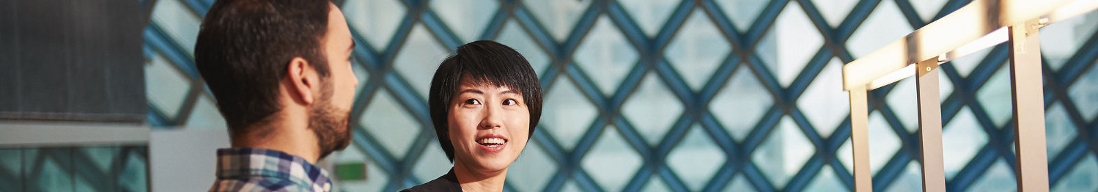 A woman and man converse in a room with many windows