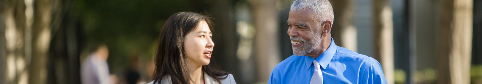 Two folks walking and talking on a sunny day