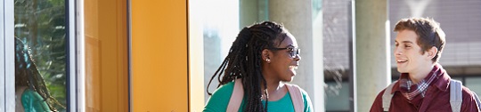Two students arrive at a campus building