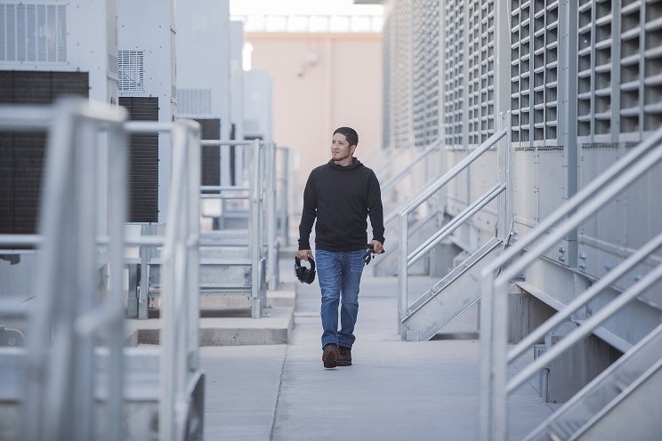 Person walking by outdoor industrial cooling units.