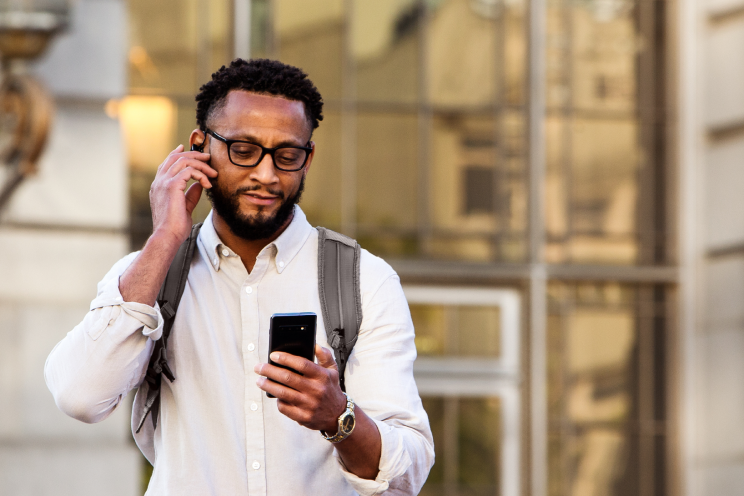 A person holding an earpiece and looking at a smart phone.