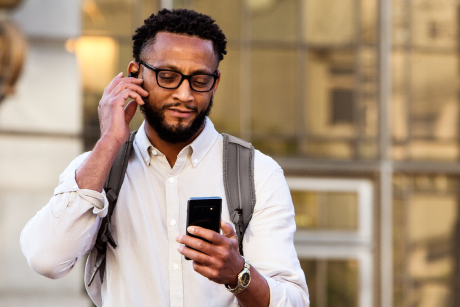 A person holding an earpiece and looking at a smart phone.